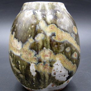 May include: A small, round ceramic vase with a mottled green, brown, and white glaze. The vase has a unique, organic look.