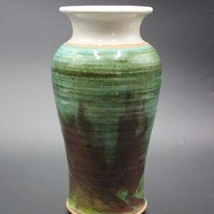 May include: A ceramic vase with a white top and a green and brown glaze. The vase has a rounded body and a narrow neck.