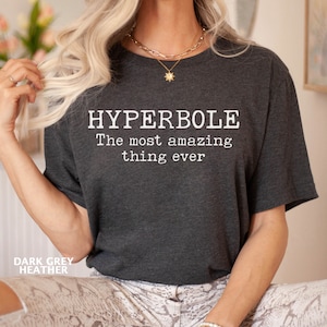 May include: A dark grey heather t-shirt with the text "HYPERBOLE The most amazing thing ever" printed in white.