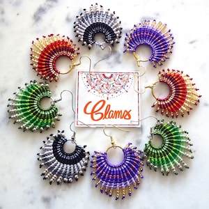May include: A set of eight handmade earrings featuring a variety of colors and patterns. The earrings are made with small beads and are shaped like a fan. The earrings are all different colors, including red, green, purple, and black. The earrings are hanging from gold hooks.