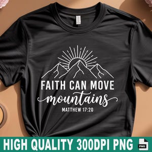 Peut inclure: T-shirt noir avec un motif blanc représentant des montagnes, un soleil et le texte "FAITH CAN MOVE mountains" avec "Matthew 17:20" en dessous. Le t-shirt est présenté sur une surface marron avec une bougie allumée et des fleurs.