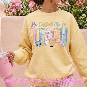 May include: A pale yellow crewneck sweatshirt featuring the text "He Called Me To TEACH" in a colorful, multi-toned font. The design includes graphic illustrations of a black and white composition notebook, a pencil, and a paper airplane.