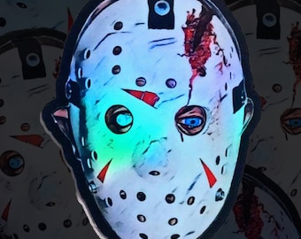 May include: A close-up of a white hockey mask with red and blue accents. The mask has a cracked and bloody appearance, suggesting a horror theme.