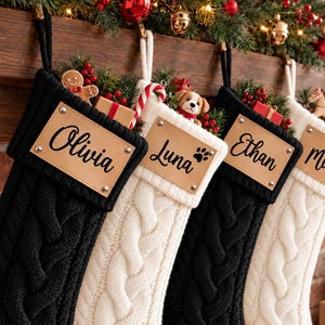 Puede incluir: Cuatro calcetines navideños de punto trenzado en colores alternos negro y blanco, cada uno con un parche de cuero rectangular con los nombres Olivia, Luna, Ethan y Milo, además de pequeñas huellas en dos de los parches.