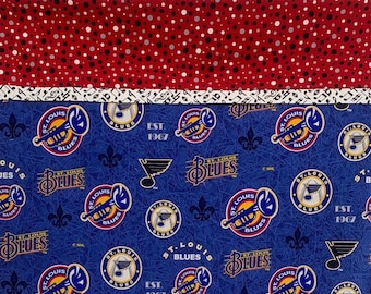 May include: Blue fabric with a repeating pattern of the St. Louis Blues hockey team logo. The logo features a gold trumpet, a blue and white hockey puck, and the words "St. Louis Blues" in gold lettering. The fabric also includes the words "Est. 1967" in gold lettering.