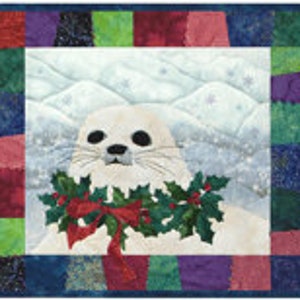 May include: A white seal with black eyes and a pink nose wearing a green holly wreath with red berries and a red bow. The seal is in front of a snowy mountain landscape.