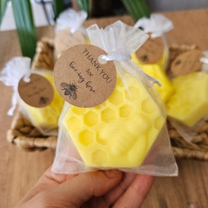 May include: A small yellow honeycomb-shaped candle in a clear organza bag with a brown tag that says "Thank you for being here".