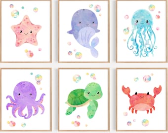 Puede incluir: Conjunto de seis impresiones de acuarela con diferentes criaturas marinas, incluyendo una estrella de mar, una ballena, una medusa, un pulpo, una tortuga y un cangrejo. Cada impresión tiene un fondo blanco con burbujas de colores.