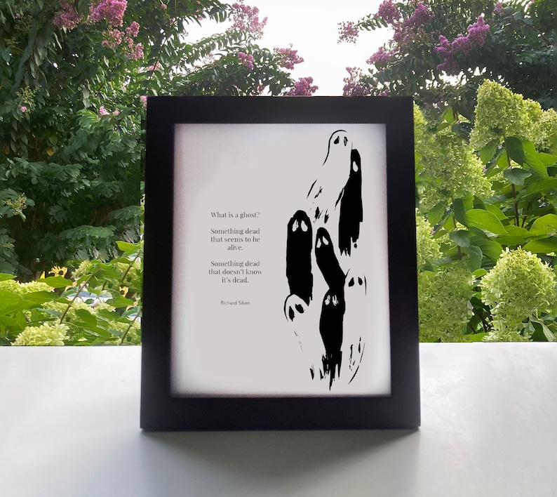 May include: A black and white framed print featuring a poem about ghosts. The poem reads "What is a ghost? Something dead that seems to be alive. Something dead that doesn't know it's dead." The poem is attributed to Richard Skelton.
