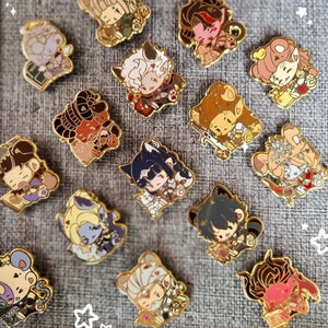 Könnte beinhalten: Eine Sammlung von 14 goldfarbenen Emaille-Pins mit verschiedenen Comicfiguren. Die Pins befinden sich auf einem grauen Stoffhintergrund. Die Figuren umfassen eine Katze, einen Hund, einen Bären, einen Fuchs und ein Kaninchen. Die Pins sind alle in verschiedenen Größen und Formen.