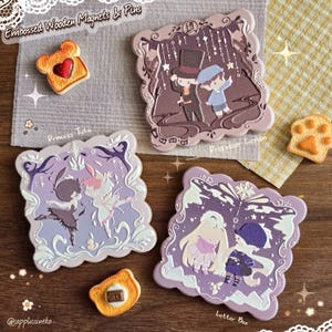 Könnte beinhalten: Geprägte Holzmagnete und -pins mit verschiedenen Designs. Das Bild zeigt einen toastförmigen Magneten mit einem Herzen und mehrere quadratische Magnete mit detaillierten Illustrationen und dem Text "Princess Tutu", "Professor Layton" und "Letter Bee".
