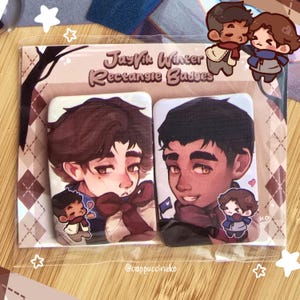 May include: Two rectangular badges featuring illustrations of male characters with brown hair and skin. The badges are packaged together and have the text "JayVik Winter Rectangle Badges". The background has a brown and white argyle pattern.
