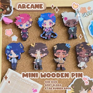 Puede incluir: Colección de mini pines de madera de 4 cm con personajes de "Arcane". Los pines tienen un acabado brillante y una parte trasera de goma con forma de estrella. Los pines muestran diseños detallados de personajes en colores vibrantes sobre un corcho.