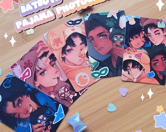 Peut inclure: Un ensemble de quatre cartes à collectionner rectangulaires intitulées BATBOYS PAJAMA PHOTOCARD, présentant des illustrations de style anime de personnages en pyjama animalier. Les cartes montrent des dessins colorés, des autocollants et un petit charme en forme de bonbon.
