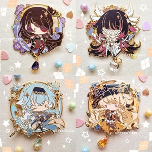 May include: Four gold-colored enamel pins featuring anime-style characters with different colored hair and outfits. Each pin has a dangling charm with a gemstone.