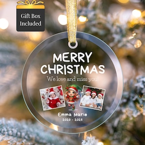 Peut inclure: Une boule de Noël ronde et transparente avec les mots "MERRY CHRISTMAS" et "We love and miss you!" imprimés dessus. L'ornement comprend trois petites photos et le nom "Emma Marie" avec les années "2020 - 2025". Il est suspendu à un ruban doré.
