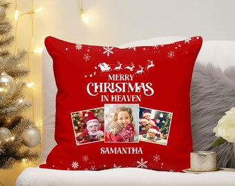 May include: A red Christmas pillow with the text "MERRY CHRISTMAS IN HEAVEN" and the name "SAMANTHA". The pillow features three framed photos and white snowflake and Santa Claus designs.