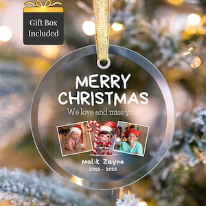 Peut inclure: Ornement de Noël rond et transparent avec l'inscription "MERRY CHRISTMAS" et "We love and miss you!". Il présente trois petites photos et le nom "Malik Zayne" avec les années 2013-2025. Un ruban doré est attaché pour l'accrocher. Une icône de boîte cadeau est en haut à gauche.