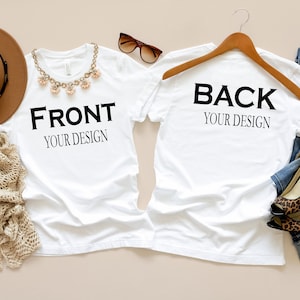 May include: Two white t-shirts with the text "FRONT YOUR DESIGN" and "BACK YOUR DESIGN". Accessories include a brown hat, a beige scarf, sunglasses, a necklace, jeans, and leopard print heels. The items are arranged on a beige surface.