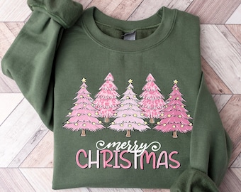 May include: A green sweatshirt with a pink and white Christmas tree design and the text "merry christmas" in pink.
