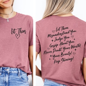 May include: A mauve t-shirt with the text "Let Them Misunderstand You. + Judge You. + Gossip About You. Never Doubt Your Worth! + Your Beauty! + Keep Shining!" printed on the back and the text "Let Them" with a heart on the front.