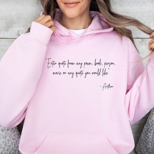 May include: Pink hoodie with a black quote that reads "Enter quote from any poem, book, person, movie or any quote you would like -Author"