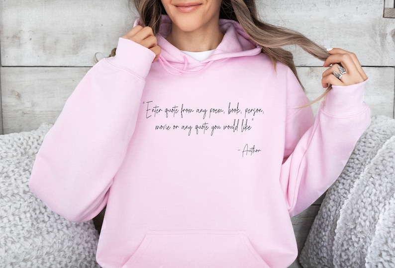May include: Pink hoodie with a black quote that reads "Enter quote from any poem, book, person, movie or any quote you would like -Author"