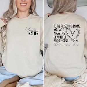 May include: A cream-colored sweatshirt with the text "You Matter" on the front and "To the person behind me: You are amazing, beautiful and enough. Remember that." on the back.