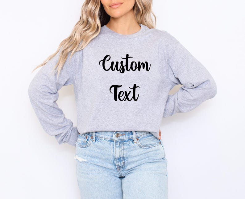 A woman wearing a grey sweatshirt with the text "Custom Text" printed on it, standing against a white background.