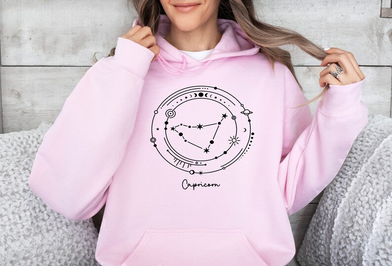 May include: Pink hoodie with a black graphic of the Capricorn constellation and the word "Capricorn" written below.