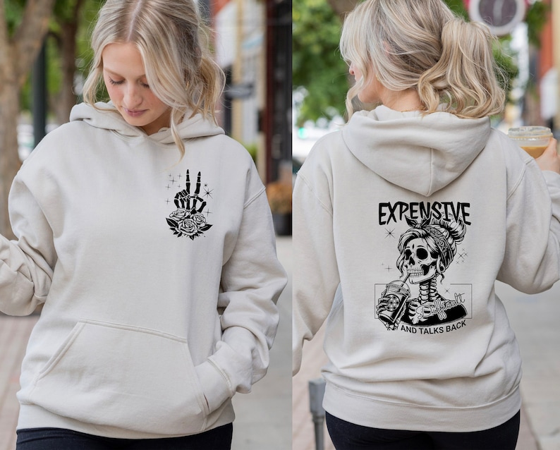 May include: A light beige hoodie with a black skeleton graphic on the back. The graphic shows a skeleton with a bandana and a drink in its hand. The text "Expensive and Talks Back" is below the graphic. The front of the hoodie has a black graphic of a hand with roses.