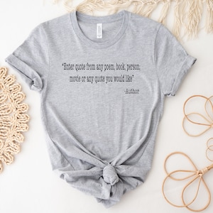 May include: Grey t-shirt with a quote that reads "Enter quote from any poem, book, person, movie or any quote you would like" -Author