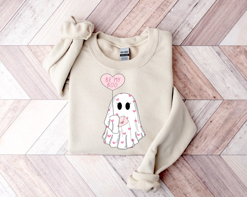 May include: A beige sweatshirt with a graphic of a ghost holding a heart-shaped balloon that says "Be My Boo".