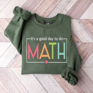 May include: A green sweatshirt with the text "it's a good day to do MATH" in a white box with colorful letters. A small pink heart is below the text.