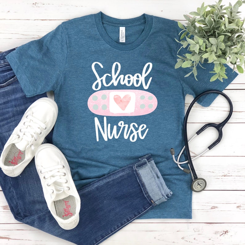 May include: A teal blue t-shirt with the text "School Nurse" in white. A pink bandage with a white heart is above the text.