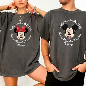 A woman and a man wearing matching t-shirts with a Mickey Mouse design pose together.