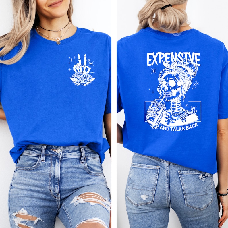 May include: A royal blue t-shirt with a white skeleton graphic on the back. The graphic shows a skeleton woman with a bandana, drinking from a cup and the text "Expensive, Difficult, and Talks Back". The front of the shirt has a white peace sign graphic with roses.