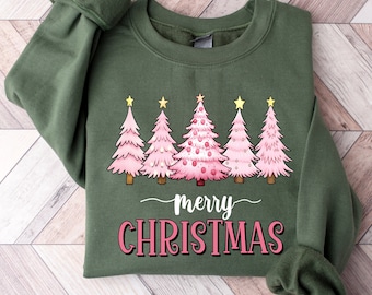 May include: Green sweatshirt with a graphic of five pink Christmas trees topped with gold stars. The words "merry CHRISTMAS" are written in white and pink script below the trees. The sleeves are cuffed.