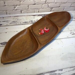 May include: A long, wooden serving tray with three separate compartments. The tray is made of dark wood and has a natural finish. There are two red and gold earrings in one of the compartments.