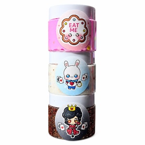Pode incluir: Quatro pequenos frascos transparentes empilhados, cada um com uma tampa branca. Os frascos contêm glitter e têm autocolantes circulares com personagens de desenhos animados e as palavras "EAT ME". O frasco superior é rosa, o segundo é branco e o inferior é castanho. Os frascos têm cerca de 5 cm de altura.