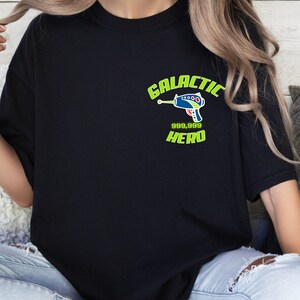May include: A black t-shirt with a green and blue graphic of a space gun and the text "GALACTIC 999,999 HERO".