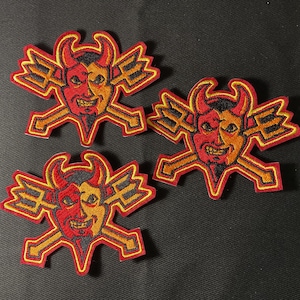 May include: Three embroidered patches with a devil face design. The devil's face is split, with one side red and the other orange. The patches have yellow and orange accents and a trident design.