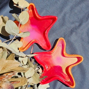 May include: Two red and orange star-shaped resin trays with a pink and gold glitter finish.