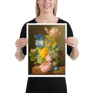 Puede incluir: Una impresión de naturaleza muerta floral con un vibrante ramo de flores. El arreglo incluye una rosa amarilla, iris azules, un tulipán a rayas rojas y blancas y otras flores coloridas. La obra de arte se muestra sobre un bloque de madera.