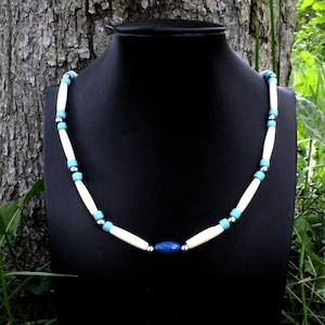 Peut inclure: Un collier de perles blanches et bleues avec une grosse perle ovale bleue au centre.