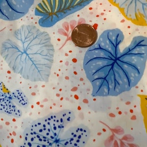 May include: White fabric with a blue, yellow, and pink leaf pattern. The fabric has a scattered pattern of small red and pink dots.