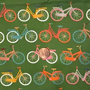 May include: Green fabric with a repeating pattern of colorful bicycles. The bicycles are in shades of pink, orange, yellow, and blue, with white wheels. The design is a whimsical and playful illustration.