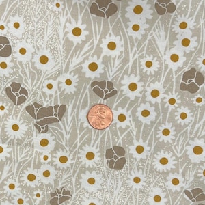 May include: Floral fabric featuring white daisies with yellow centres and brown poppy-like shapes on a beige background. White stems and leaves are also present. A penny is included for scale.