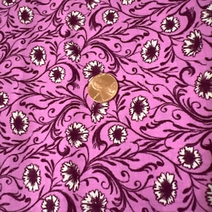 以下が含まれることがあります： 白と濃い紫の花柄のピンク色の生地。生地には小さな花と蔓が繰り返し描かれています。