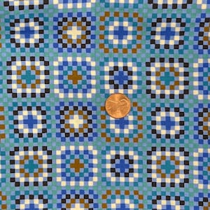 May include: A close-up of a fabric with a repeating geometric pattern. The design features squares in shades of blue, teal, brown, black, and white. The pattern is reminiscent of a mosaic or pixelated design. A penny is in the image for scale.